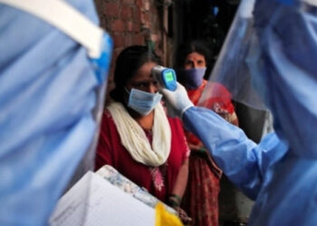 Health Care Worker Checking a Women's temperature Photo Credit: Francis Mascarenhas / Reuters