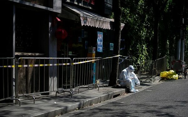 A worker in a protective suit rests on a street during a lockdown, amid the coronavirus disease (COVID-19) pandemic, in Shanghai, China (Photo Source: Reuters/ Aly Song)