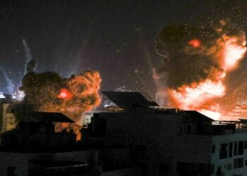 Explosions light-up the night sky above buildings in Gaza City as Israeli forces shell the Palestinian enclave, early on May 18, 2021. - Israeli jets kept up a barrage of air strikes against the Palestinian enclave of Gaza as a week of violence that has killed more than 200 people pushed world leaders to step up mediation. (Photo by MAHMUD HAMS / AFP)