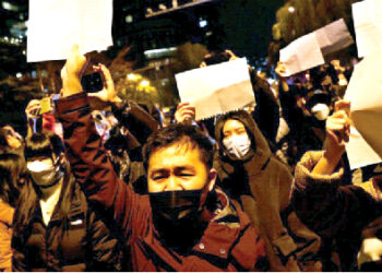 People gather for a vigil and hold white sheets of paper in protest against COVID-19 restrictions, as they commemorate  victims of a fire in Urumqi