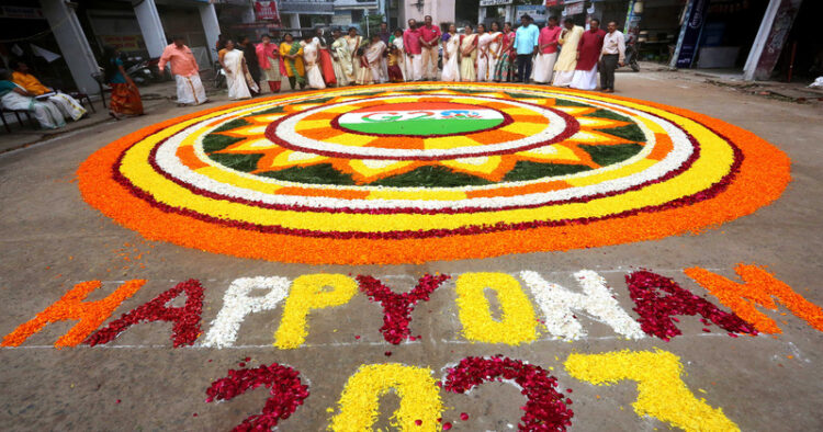 Malayali community members decorate 'Pookalam', a rangoli made with fresh flowers, as part of the celebration of Onam festival