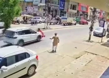 Screenshot taken from the viral video, the woman in red dress can be seen over the bonnet of the car (HT)