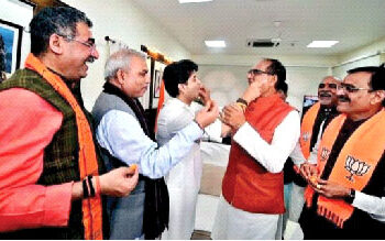 Union Civil Aviation Minister Jyotiraditya Scindia and Madhya Pradesh Chief Minister Shivraj Singh Chouhan offer sweets to each other as they celebrate the party's victory in the State Assembly elections, as BJP State chief VD Sharma and others look all