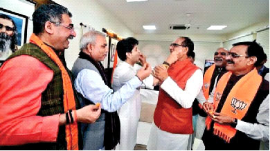 Union Civil Aviation Minister Jyotiraditya Scindia and Madhya Pradesh Chief Minister Shivraj Singh Chouhan offer sweets to each other as they celebrate the party's victory in the State Assembly elections, as BJP State chief VD Sharma and others  look all