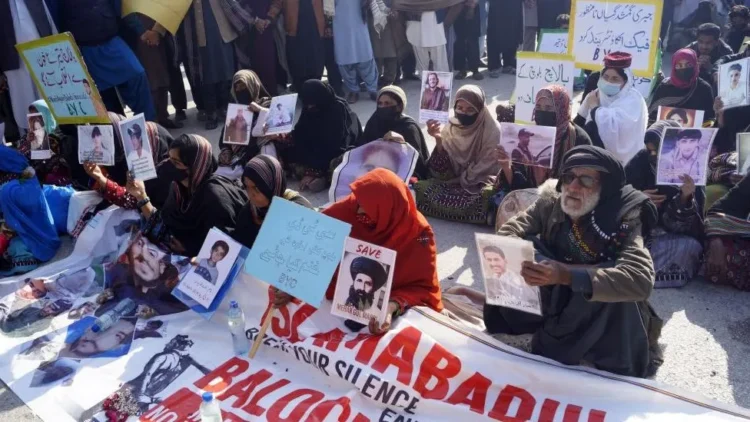 Protesters hold photos of their missing relatives, during a protest (BBC)