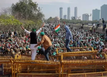 Farmers climb a police barricade during a protest in Delhi (Source: Reuters)