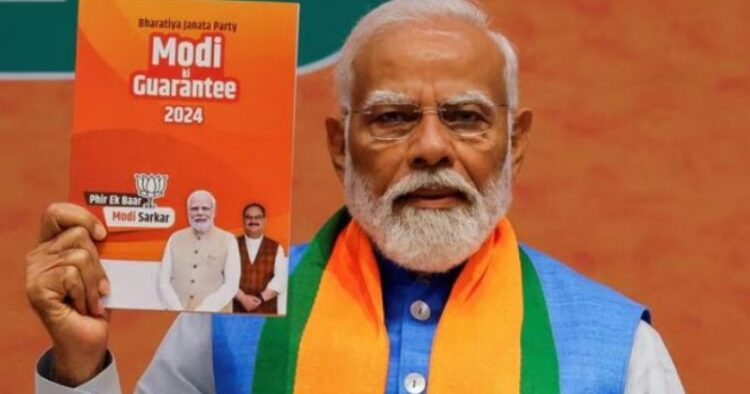 PM Narendra Modi with a copy of BJP's Sankalp Patra