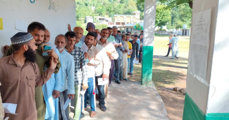 Voters standing in a queue to exercise their right to vote at a polling station in Anantnag