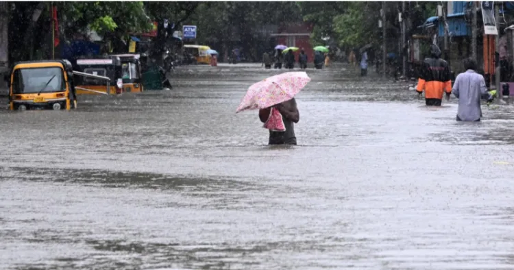 A man with an umbrella wades his way through flooded street