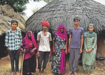 The boy in the blue t-shirt is Shravan Kumar, standing outside his house with his family, after clearing NEET UG 2025