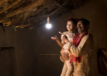 Rural Indian father with daughter delighted at the glow of light bulb and electricity reaching their home after long wait (Photo: istock)