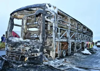 Charred remains of a passenger bus lie on a highway in Chinnatekuru village, where it caught fire early Friday after a collision with a motorbike, near Kurnool district