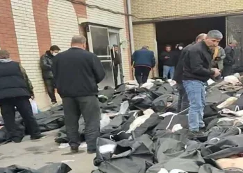 Bodies lie in body bags on the ground as people stand amid the scene outside Kahrizak Forensic Medical Centre in Tehran, Iran