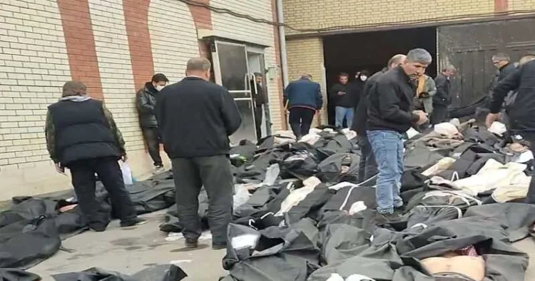 Bodies lie in body bags on the ground as people stand amid the scene outside Kahrizak Forensic Medical Centre in Tehran, Iran