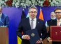 Indian and German officials exchange signed documents during a critical minerals agreement ceremony in January 2026, with PM Modi & Chancellor Friedrich Merz in the background