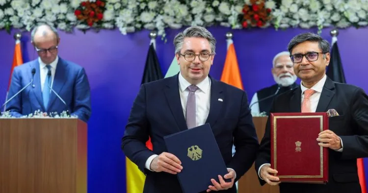 Indian and German officials exchange signed documents during a critical minerals agreement ceremony in January 2026, with PM Modi & Chancellor Friedrich Merz in the background