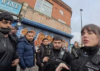 A police officer addresses a group of men during a tense exchange in Whitechapel, London