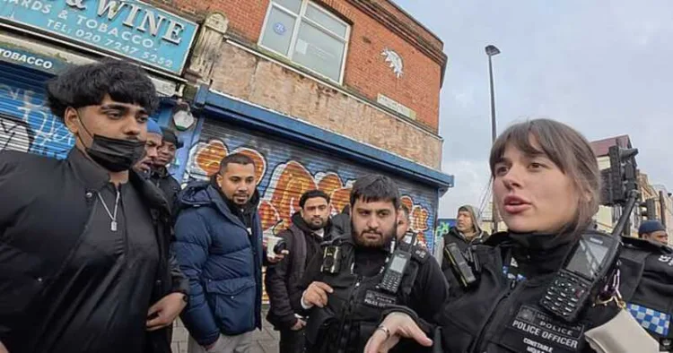 A police officer addresses a group of men during a tense exchange in Whitechapel, London
