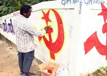 CPI(M) workers paint the party’s hammer and sickle symbol on a roadside wall as part of election campaign preparations in Kerala