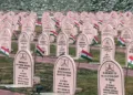 Drass, Jul 25 (ANI): A view of rows of memorial headstones adorned with National flags as preparations underway ahead of the 27th Kargil Vijay Diwas on July 26, in Drass on Saturday. (ANI Video Grab)