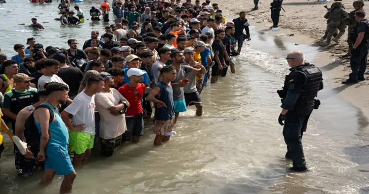 Spanish security personnel monitor migrants arriving on the coast of Ceuta amid a fresh wave of sea crossings from Morocco