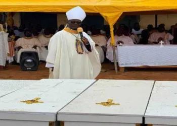 A Christian cleric addresses mourners during a funeral service beside the coffins of victims killed in recent attacks in Nigeria's Middle Belt