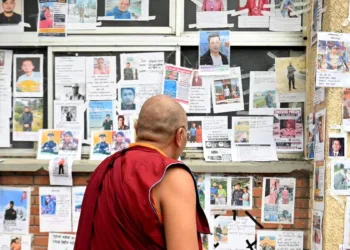 A Buddhist Monk looking at the pictures of lost and missing people outside Tribhuvan University Teaching Hospital