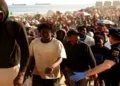 Migrants are escorted to official shelters after authorities clear a makeshift beach camp following a mass crossing from Morocco in Ceuta, Spain, on August 20, 2026