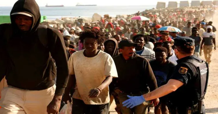 Migrants are escorted to official shelters after authorities clear a makeshift beach camp following a mass crossing from Morocco in Ceuta, Spain, on August 20, 2026